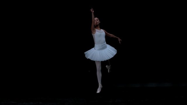 Ballerina performing on black background spinning slow motion