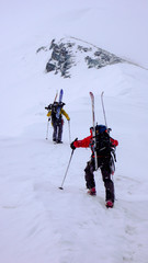 two male mountain climbers on a backcountry ski mountaineering tour in bad weather