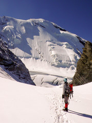 single male mountain climber looks at a steep north face he has just climbed