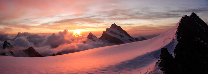 panoramic view of gorgeous pink sunrise over glacier and high mountain peaks in the Alps