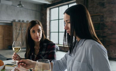 Two girlfriends have dinner drink wine home