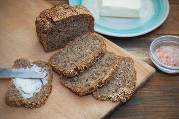 Whole Grain Bread with Seeds. Breakfast. fitness Diet Bread Sliced with Butter. Wooden board.