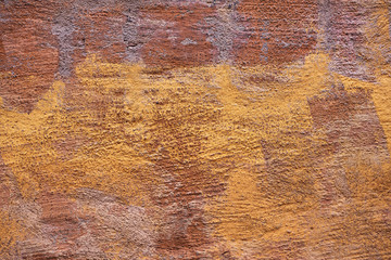 Multicolored stonewall with plaster in yellow and brown, detailed and weathered surface
