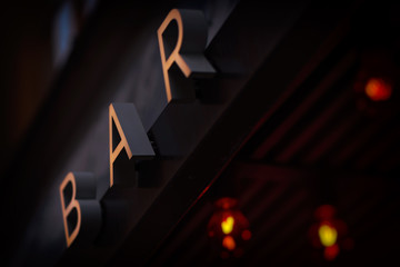 Sign with the letters BAR in gold and red lights in defocus in background