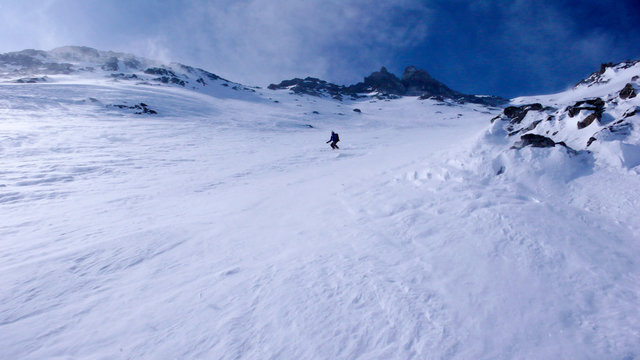 extreme skier in the back country on a very steep north face descent in the Alps in high winter