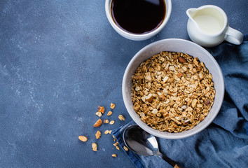 Top view of Helathy Breakfast - granola, milk, cup of coffee on blue stone table. Copy space for text. Food Healthy Background.