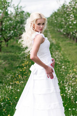 young pretty bride with curls n white wedding dress outdoors, view from behind