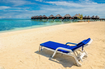 A blue deckchair on the background of exotic huts on the water