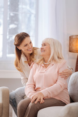 Obraz premium Wonderful mood. Cheerful positive nice women smiling to each other and expressing their emotions while being at home