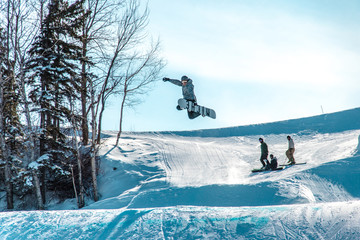 snowboarder grabbing his board in the air being watched by his friends