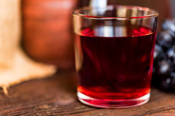 Red grape juice in glass and grapes close