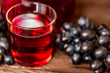 Red grape juice in glass and grapes close