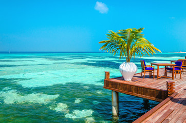 An exotic view of a wooden restaurant on stilts on a background of azure water and blue sky