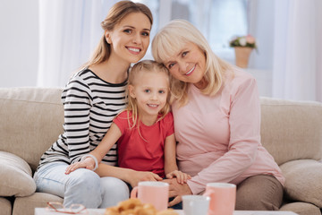 Obraz premium Female generations. Nice happy joyful family sitting together and looking at you while being at home