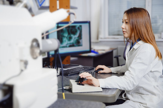 Young student woman working at computer on an electronic microscope, studying the structure of metals and structure of 3d printing.