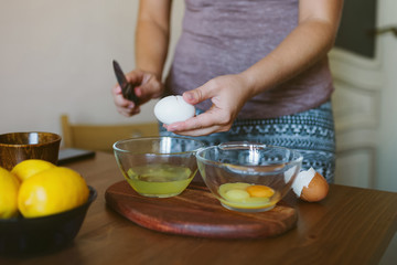Obraz na płótnie Canvas Woman's hands cracking a whole egg into a bowl.