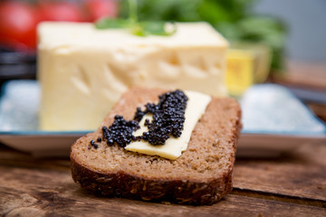 Natural food and ingredients, breakfast with butter, bread and black caviar on wooden background