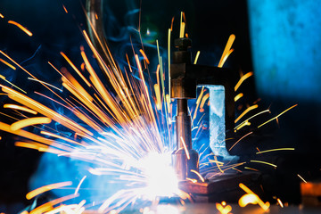 Robot is welding metal part in factory

