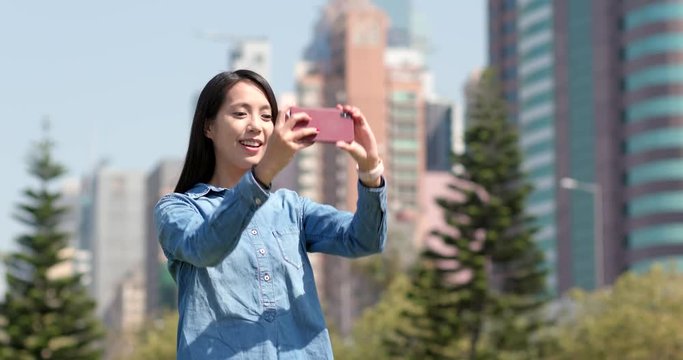 Woman taking photo with cellphone in city