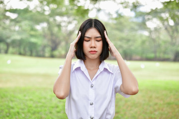 Education Concepts. Beautiful young Asian girl is thinking seriously. Beautiful Asian students are thinking in the garden. Beautiful young student is headache in the garden.