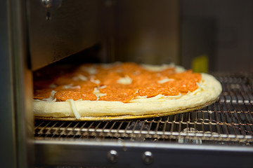 Cooking of pepperoni pizza in the oven.