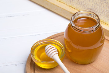 Honey with wooden honey dipper on wooden table