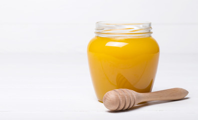 Honey with wooden honey dipper on wooden table