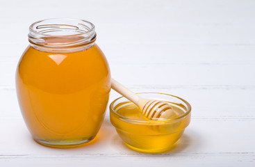 Honey with wooden honey dipper on wooden table