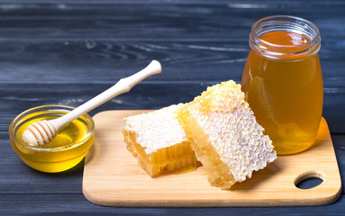 Honey with wooden honey dipper on wooden table