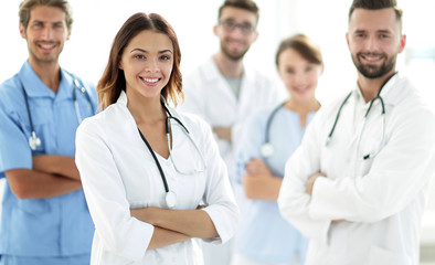 Fototapeta premium Attractive female doctor with medical stethoscope in front of medical group