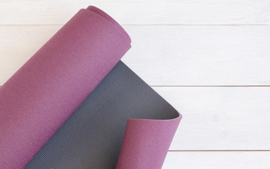 Yoga accessories,  exercise mat on white wooden background with copy space. Concept for ashtanga yoga practice.