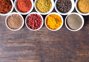 colorful spices in ceramic containers on a dark background