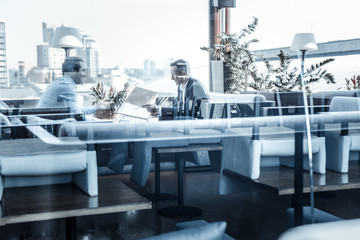 Important meeting. Blurred image of two businessmen sitting opposite each other and talking while having a meeting