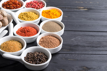 colorful spices in ceramic containers on a dark background