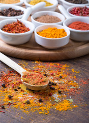 Colorful spices in spoons on dark wooden background, Top view