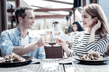 Romantic meeting. Nice pleasant young people holding glasses and drinking wine while having a date