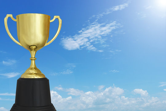 Gold winner cup on blue sky with white clouds background