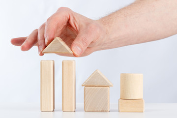 the hand of man builds a house out of children's blocks