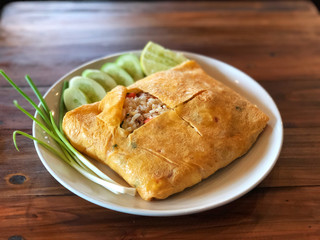 Fried Rice Wrapped in Egg on wooden table with natural sunlight, delicious of Thai food , Name of this menu in Thailand : 