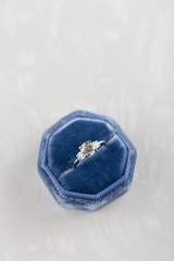 White golden wedding ring with diamonds in blue vintage velvet ring box on white background