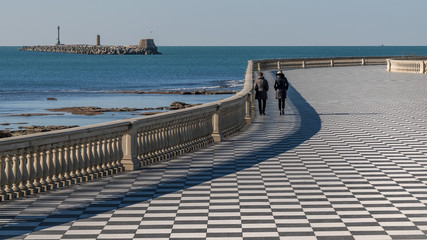 Two women walk on the Mascagni Terrace in Livorno on a beautiful sunny day, Tuscany, Italy