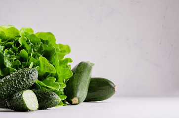 Deep green different vegetables on soft white wood table with copy space. Healthy summer raw food.