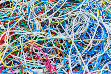 The bunch of electric wires or cables are strongly tangled together. Remnants of wires of different colors, piled in a big pile. On the wires there are compressed ferrules for connection.