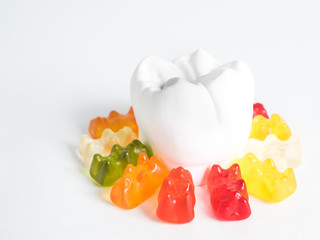 The gypsum tooth surrounded by gummy bears against a white background