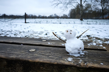 Piccolo pupazzo di neve su una panchina di legno