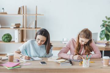 female multiethnic students writing examination together