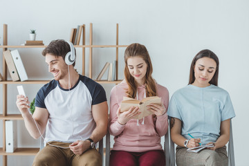 Obraz premium young students listening music, reading book and writing in copybook