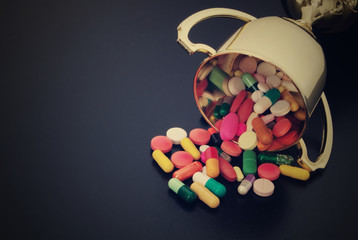 Golden winner cup with doping pills on black table with room for text, doping in sport concept. 