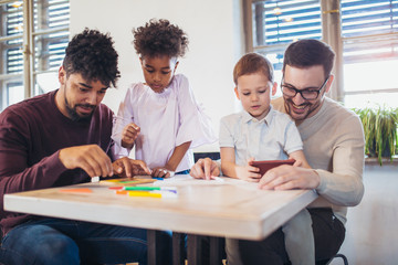 Two fathers play educational games with their children, having fun.