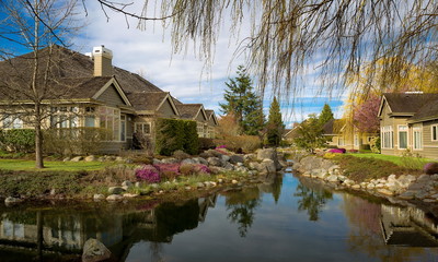 Fototapeta na wymiar Residential district at the outskirts of the city of Tsawwassen, a town of cottages at a picturesque location, cottages stand among ponds and colorful flower beds